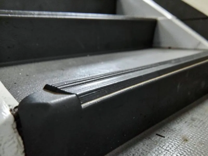 Rubber stair tread detail with integrated nosing and contrasting visual strip on an institutional stairwell