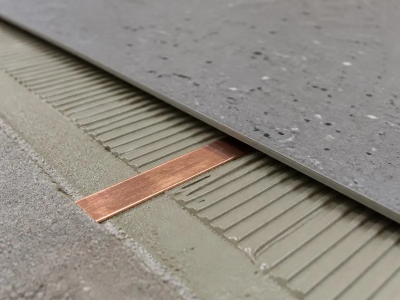 Static-dissipative tile assembly detail with copper grounding strip in conductive adhesive